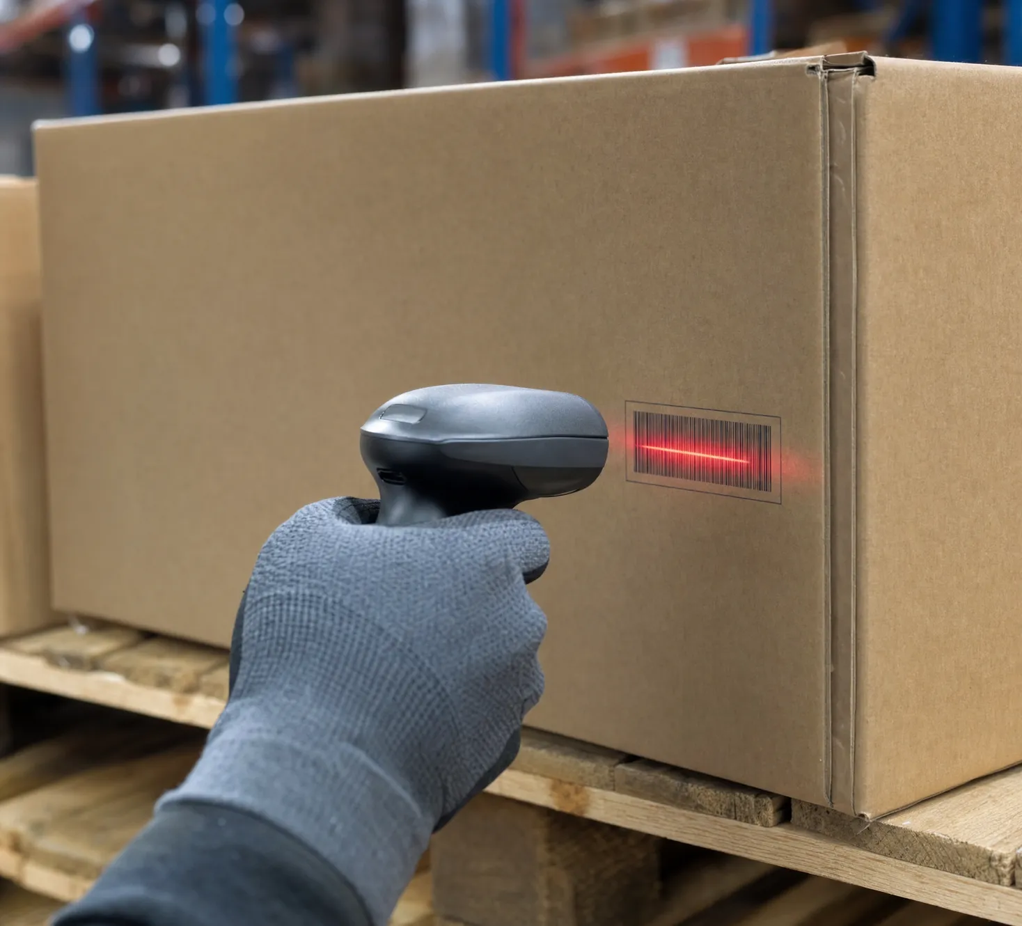 Gloved hand scanning a carton barcode on a warehouse pallet